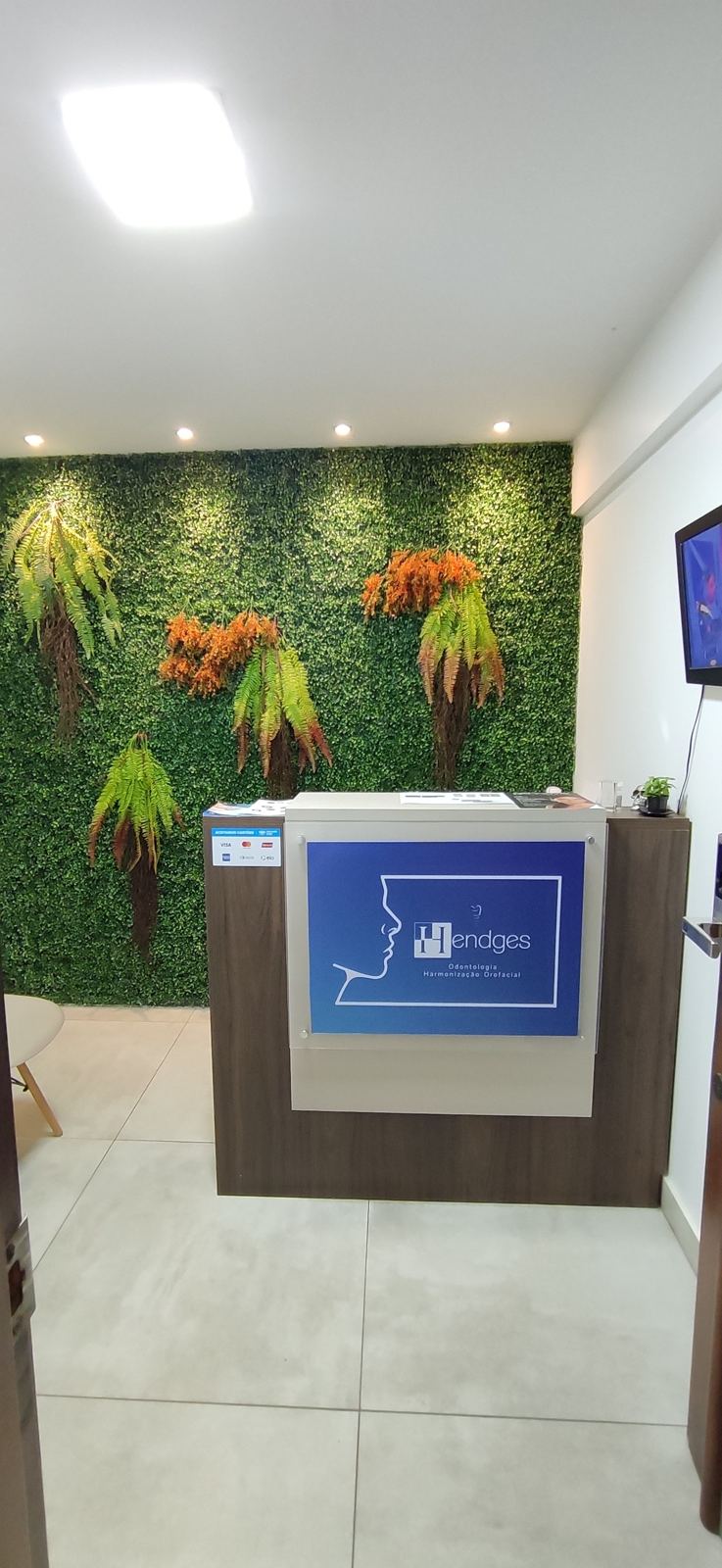 Recepção da Hendges Odontologia com parede verde e balcão com o logotipo